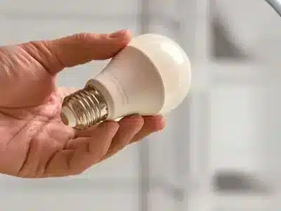 LED-Lampe in Hand über Mülleimer