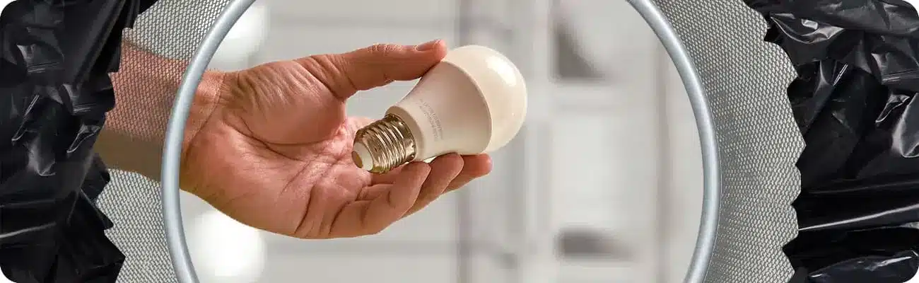 LED-Lampe in Hand über Mülleimer
